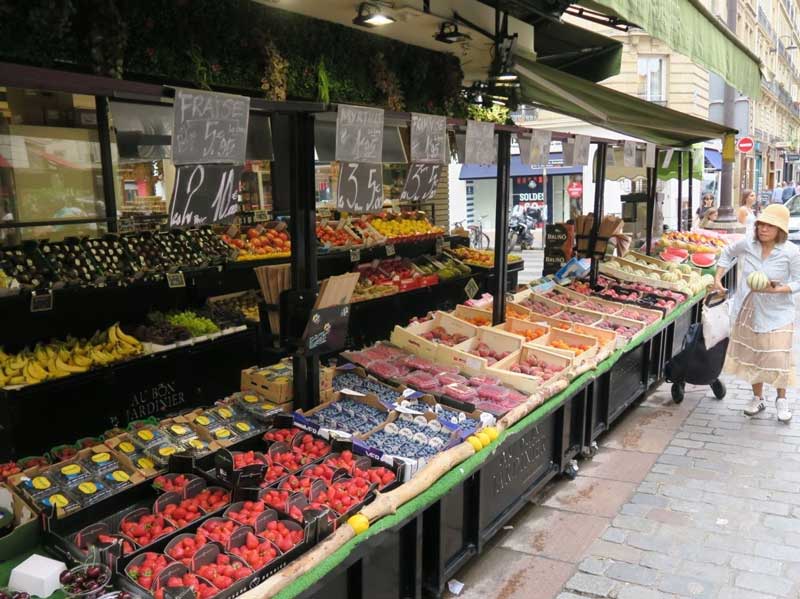 Een gezellige marktstraat in Parijs: Rue Cler. Op de foto een local uit Parijs voor een marktkraam met groente